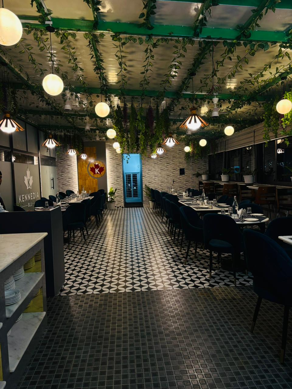 Long dining hall with patterned floor and hanging greenery
